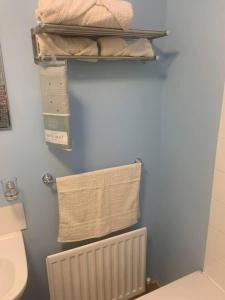 y baño con aseo, toallas y radiador. en Beautiful 2-Bed House in Larne with free parking, en Larne
