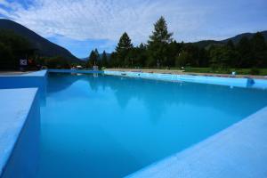 ein großer Pool mit blauem Wasser und Bergen im Hintergrund in der Unterkunft Hotel SOREA MÁJ in Liptovský Ján