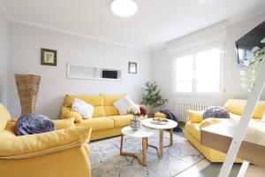 sala de estar con sofás amarillos y mesa en Casa Flor Delfin Ribadeo, en Ribadeo