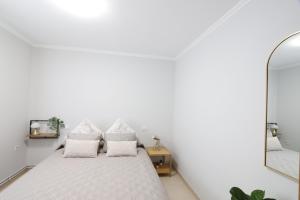 a white bedroom with a bed and a mirror at Casa Flor Delfin Ribadeo in Ribadeo