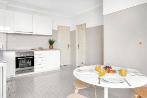 una cocina blanca con una mesa con platos de comida. en Wonderful Shared Apartment in Alfornelos - NEAR METRO! en Lisboa