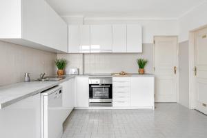 una cocina blanca con armarios y electrodomésticos blancos en Wonderful Shared Apartment in Alfornelos - NEAR METRO! en Lisboa