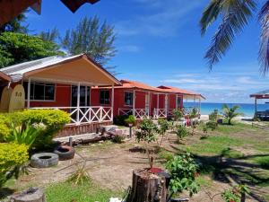 ein rotes Haus mit dem Ozean im Hintergrund in der Unterkunft Tumombuvoi Homestay (Sidi place) in Tiga Papan