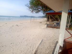 a beach with a building and chairs on it at Tumombuvoi Homestay (Sidi place) in Tiga Papan