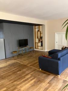 a living room with a blue couch and a television at Loft me - Entre art deco et loft à l'americaine in Périgueux