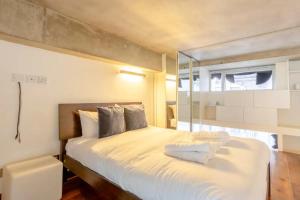a bedroom with a large white bed with a window at Incredible 2BD Loft by Regents Canal - Haggerston in London