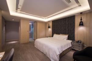 a bedroom with a large white bed and a chair at U-Her Hotel in Taichung