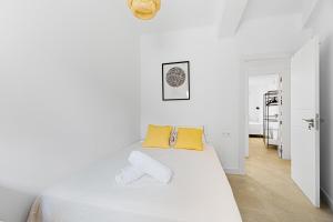 Dormitorio blanco con cama blanca y almohadas amarillas en Pineapple Canasteros 7, en Málaga