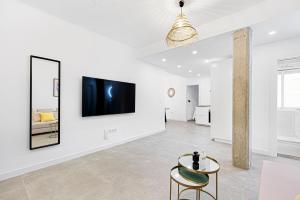 Una sala de estar con una mesa y un televisor en una pared. en Pineapple Canasteros 7, en Málaga