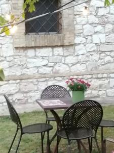 una mesa y sillas en un patio con una pared de piedra en B&B La Giara di Assisi, en Asís