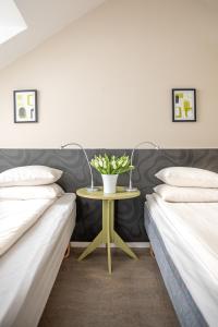 two beds with a table with a vase of flowers on it at Hotel Kupolen in Borlänge