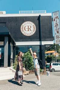 dos mujeres frente a un edificio en Global Resort Misen - グローバルリゾート弥山, en Hatsukaichi