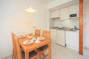 a kitchen with a wooden table with plates and fruit on it at Apartamento Via Alemanya Standard A in Can Picafort