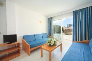 een woonkamer met een blauwe bank en een tv bij Apartamento Via Alemanya Standard C in Can Picafort