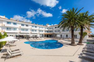 een hotel met een zwembad en palmbomen en stoelen bij Apartamento Via Alemanya Standard C in Can Picafort