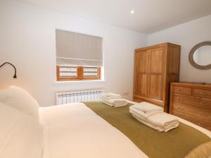 a white bedroom with a bed and a wooden dresser at Lapwings in Fareham