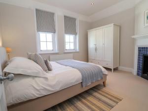 Un dormitorio blanco con una cama y una chimenea. en Runton, en Aldeburgh