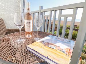 una botella de vino y dos copas y un libro sobre una mesa en Runton, en Aldeburgh