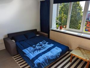 a bedroom with a bed with a blue blanket and a window at Lost & Found 3 - with 4 bikes in Pāvilosta