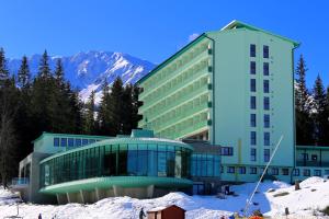 un grand bâtiment dans la neige devant une montagne dans l'établissement Hotel SOREA SNP, à Demänovská Dolina