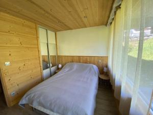 een slaapkamer met een bed in een houten kamer bij Appartement Crest-Voland, 2 pièces, 4 personnes - FR-1-733-110 in Crest-Voland