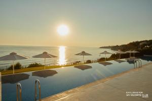 une grande piscine avec des parasols et l'océan dans l'établissement AluaSoul Zakynthos - Adults only - All Inclusive, à Tragaki