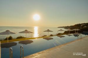 a large swimming pool with umbrellas and the ocean at AluaSoul Zakynthos - Adults only - All Inclusive in Tragaki