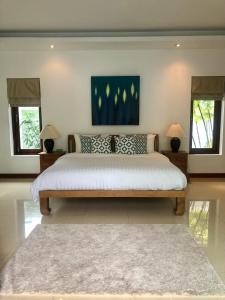 Un dormitorio con una cama grande con dos ventanas. en Baan Tai Tara 3, en Ban Tai