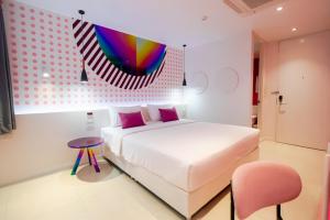 a bedroom with a white bed and a colorful painting at Budacco The Living Place in Bangkok
