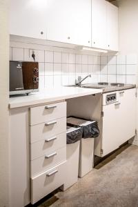 a white kitchen with white cabinets and a sink at Hotel Kupolen in Borlänge