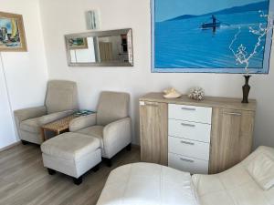 Zimmer mit 2 Stühlen, einer Kommode und einem Spiegel in der Unterkunft Apartments By The Sea in Pula
