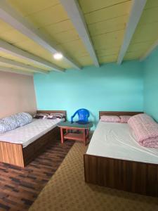two beds in a room with a blue wall at Mount Mahabharat Homestay in Panaoti