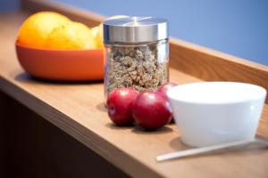 a table with a jar of nuts and cherries and a bowl of fruit at Brera Serviced Apartments Singen in Singen
