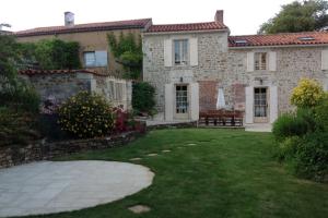 a large stone house with a grass yard at le Moulin de Garreau in Saint-Martin-des-Fontaines