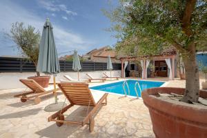 una piscina con sillas y sombrillas junto a una piscina en Luxury Rustic Villa Hvar island en Vrbanj