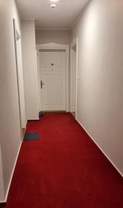 pusty korytarz z czerwonym dywanem i białymi drzwiami w obiekcie Apartament Vilda 2 w Poznaniu