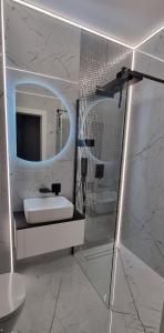 W białej łazience znajduje się umywalka i lustro. w obiekcie Apartament Vilda 2 w Poznaniu