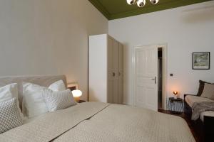 a bedroom with a white bed and a chair at Smaragd Residence Zagreb Downtown in Zagreb