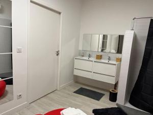 een witte badkamer met een wastafel en een spiegel bij Destination Confidentielle in Clermont-Ferrand