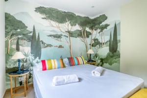 1 dormitorio con 1 cama blanca y una pintura en la pared en Superbe T4 -Vue Mer- Tout Confort Refait à Neuf! en Bormes-les-Mimosas