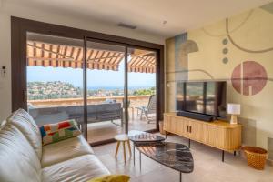 a living room with a couch and a tv and a balcony at Superbe T4 -Vue Mer- Tout Confort Refait à Neuf! in Bormes-les-Mimosas