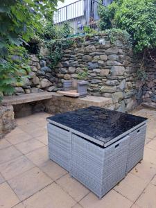 a stone wall with a bench and a trash can at Hendre Coed Isaf Caravan Park in Barmouth