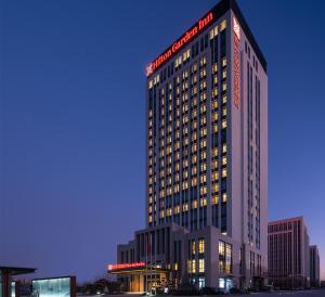 ein hohes Gebäude mit einem Schild an der Seite in der Unterkunft Hilton Garden Inn Liaocheng Jiangbei Shuicheng in Liaocheng