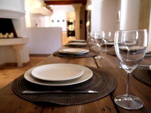 a wooden table with plates and wine glasses on it at La Bergerie Provencale - Luberon - Provence - villa with heated pool in Roussillon