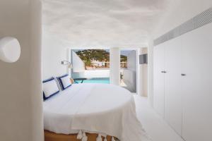 a white bedroom with a large white bed and a window at Hotel Isabella's Llafranc in Llafranc