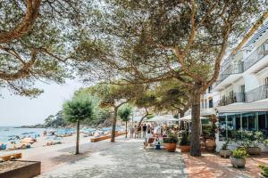 a street next to a beach with people and buildings at Hotel Isabella's Llafranc in Llafranc