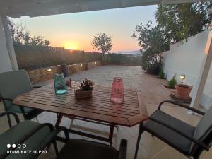 einen Holztisch mit Vasen auf einer Terrasse in der Unterkunft Andrew's sunset view apartment in Loutraki