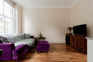 a living room with a purple couch and a tv at flat C 1-Bed Flat in Primrose Hill wont be avilbe in London