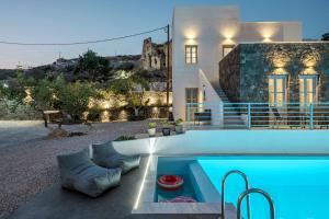 a villa with a swimming pool in front of a house at BlackStone Luxury Suites in Emporio Santorini