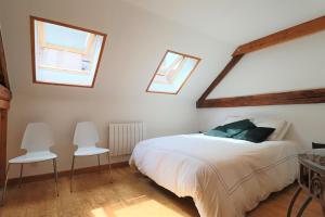 1 dormitorio con 1 cama y 2 sillas blancas en Superbe appartement esprit chalet, en Barcelonnette